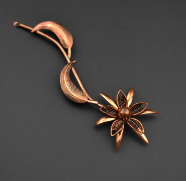 Siyah arka planda bakırdan yapılmış broş. El yapımı..