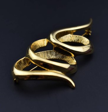 Koyu arkaplanda güzel altın bir broş..