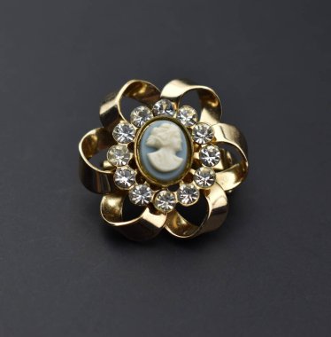 Siyah zemin üzerinde değerli taşlar olan güzel altın bir broş..