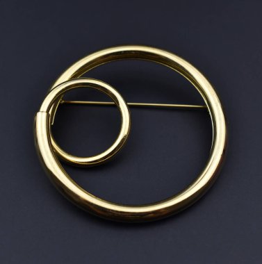 Siyah arka planda altın broş, yakın plan, üst manzara.