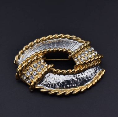 Siyah arka planda değerli taşları olan altın broş.