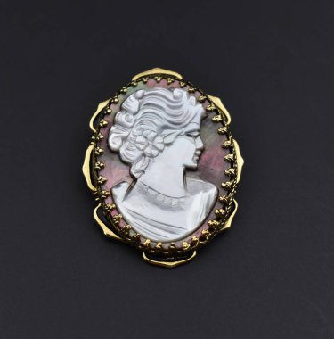 Siyah arkaplanda küçük bir simge resmi olan gümüş broş.