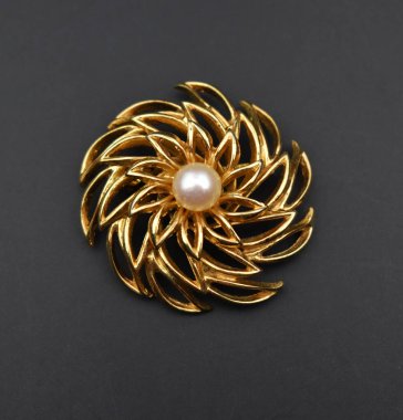 Siyah arka planda incili altın broş, yakın plan.