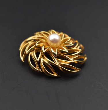 Siyah arka planda incili altın broş.