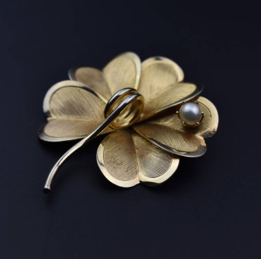 Siyah arkaplanda altın çiçek klipsi, yakın plan çekim