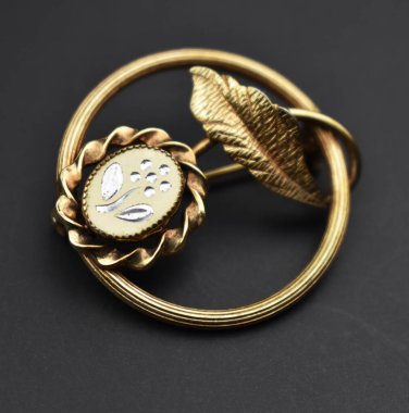 Siyah arka planda altın yapraklı mücevher broşu..