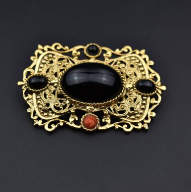 Siyah arka planda değerli taşları olan mücevher broşu..