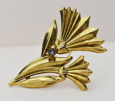 Beyaz arka planda elmaslı altın broş.