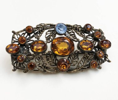 Beyaz arka planda değerli taşları olan klasik bir broş.