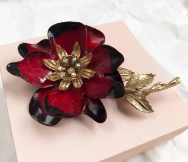 Beyaz arka planda altın ve siyah boncuklu kırmızı çiçek.