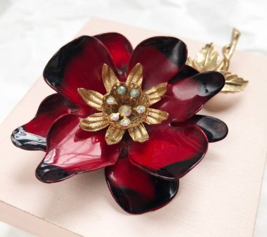 Pembe hediye kutusunda altın süsleri olan kırmızı çiçek..