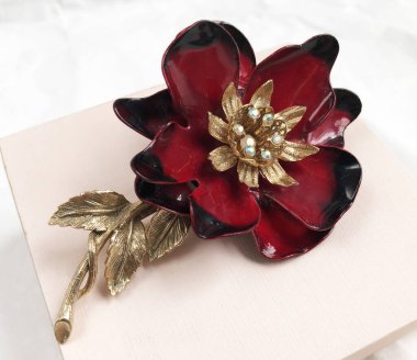 Beyaz arka planda kırmızı ve altın çiçekli el yapımı broş.