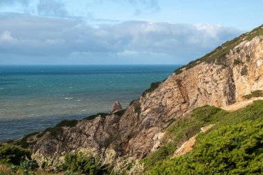 Bulutlu bir günde kayalıklarla ve denizlerle kıyı manzarası.