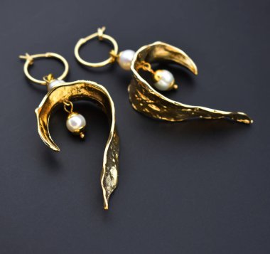 Siyah arka planda incili altın küpeler.