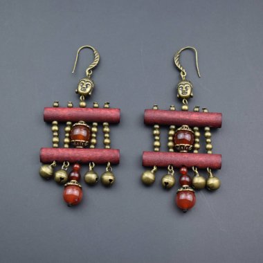 Gri arkaplanda kırmızı ve altından yapılmış küpeler.