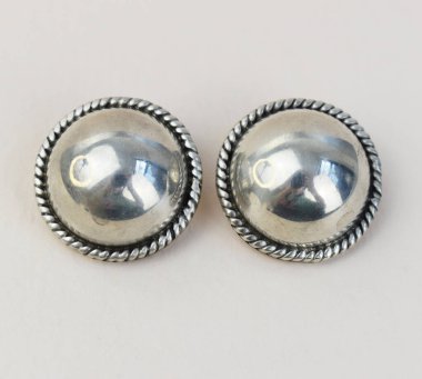 Beyaz arkaplanda bir çift gümüş küpenin yakın çekimi