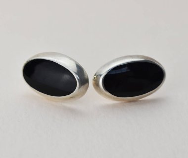 Beyaz arka planda siyah ve gümüş küpeler..