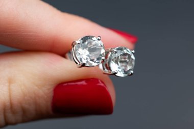 Gri arka planda yakın plan elmas küpeler.