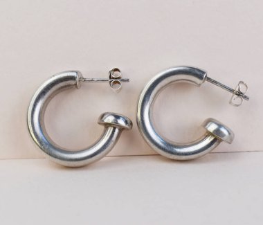 Beyaz arka planda bir çift gümüş küpe. Mücevher aksesuarları.