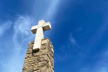 Taştan bir duvarda beyaz bulutlu mavi bir gökyüzüne karşı çapraz.