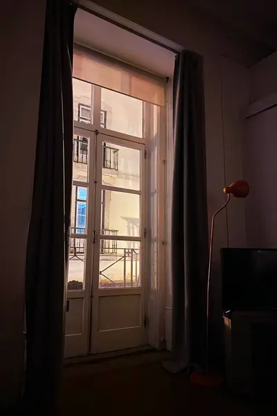 Perdeleri ve şehir manzarası olan karanlık bir odada pencere.