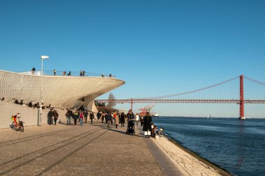 Lizbon, Portekiz, insanlar güneşli bir günde kıyı boyunca yürür, Belem bölgesinde modern bir set.