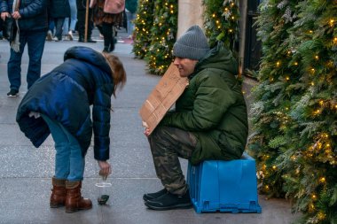 Beşinci Cadde 'deki bir adama sadaka veren bir kız. Fakir New York sokak fotoğrafçılarına yardım ediyor. Manhattan, New York, New York, ABD. 