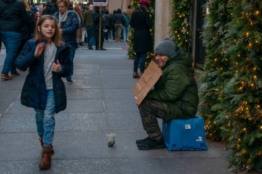 Beşinci Cadde 'deki bir adama sadaka veren bir kız. Fakir New York sokak fotoğrafçılarına yardım ediyor. Manhattan, New York, New York, ABD. 