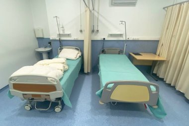 İçinde yataklar, masalar ve tıbbi malzemeler olan bir hastane odası.