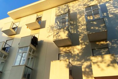 Mavi gökyüzü olan güneşli bir günde modern apartman binaları. Modern bir apartmanın cephesi