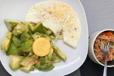 Beyaz tabakta avokadolu sahanda yumurta. Sağlıklı kahvaltı..