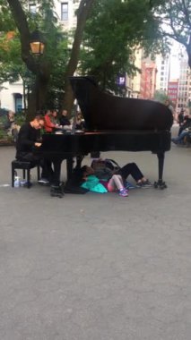 Bir adam New York 'ta bir parkta kuyruklu piyano çalıyor. ABD