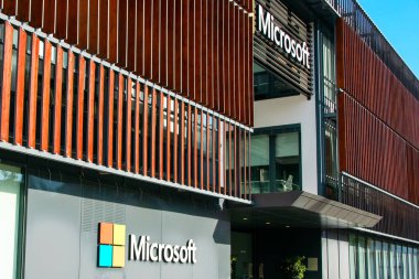 Microsoft logosu ve metin imzası ofis binasının önünde