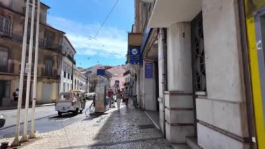 Lizbon sokaklarında yürüyen insanlar, ünlü kültürel simgeler taşıyorlar..