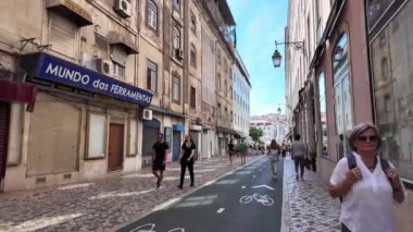 Lizbon sokaklarının tadını çıkaran turistler ve arka planda simgesel simgeler.