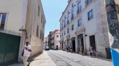 Ziyaretçiler Lisbons caddelerinde geziniyor ve ikonik simgelerde duruyor.