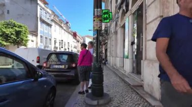 Lizbon sokaklarını gezen turistler, görünürde ünlü simgelerle.