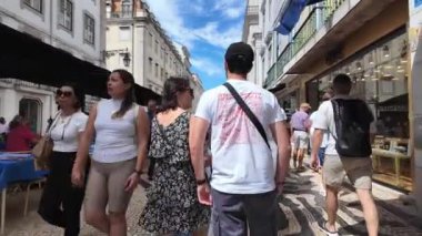 Lisbons sokaklarını gezen ve ünlü simgeleri ziyaret eden insanlar.