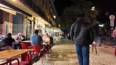 Lizbon 'da parıldayan simgeler, geceleri şehrin cazibesinin tadını çıkaran insanlar..