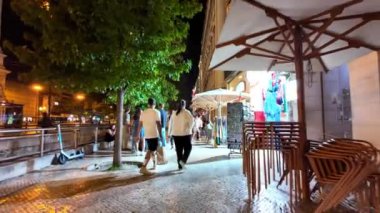Lizbon 'da gece vakti, gezginler parlak simgeler arasında tarihi araştırıyorlar..