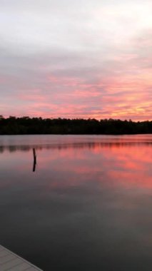 Batan güneş, orman ve nehirle çevrili göle renkli bir yansıma yapıyor..