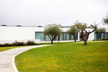 Modern binanın önündeki çimenli ve beton yollu açık hava parkı.