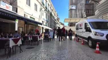 Mutlu insanlar güneşli Lizbon 'da eski evlerin yanında yürürler.