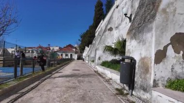 Mavi gökyüzünün altındaki sokakları keşfeden gezginlerle dolu eski Lizbon mahallesi