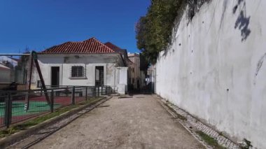Lizbon 'da güneşli bir gün. Turistler antik binaların ve renkli evlerin etrafında yürüyor.