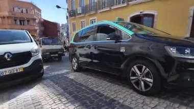 Turistler klasik evleri ve parlak güneşi olan eski kasabadaki dar Lizbon sokaklarını keşfediyorlar.