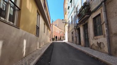 Lizbon eski kasaba manzarası güneşli Portekiz gününde renkli tarihi binaların önünden geçen insanlar