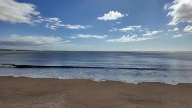 Kasvetli gökyüzü altında okyanus dalgaları olan boş kumlu sahil dramatik arka plan videoları için mükemmel.