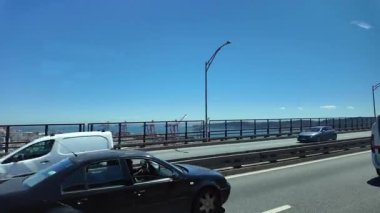 Lizbon 'da şehir arabaları, yol trafiği, gökyüzü ve manzaralı şehir atmosferiyle köprü gezisi.