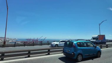 Köprü trafiğinde araç POV ile Lizbon 'a yolculuk. Şehir silueti ve kentsel titreşimler.